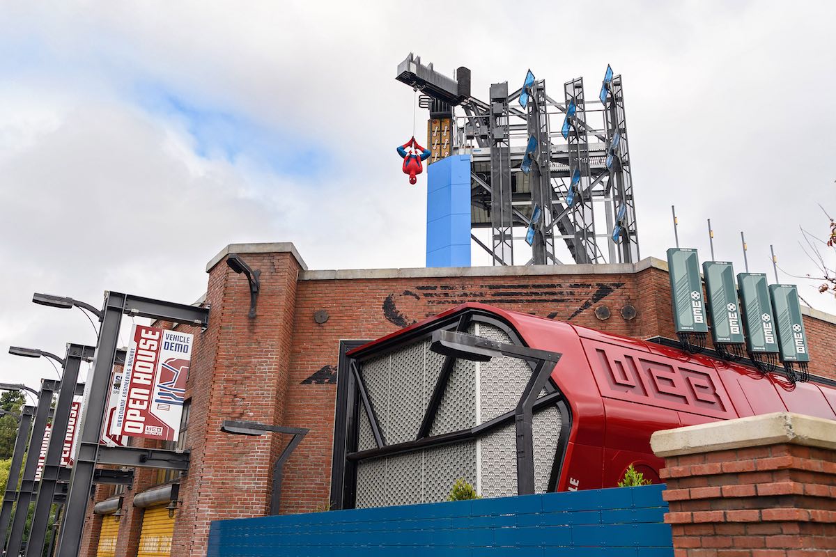 Outside view of the WEB SLINGERS A Spider-Man Adventure attraction with Spider-Man dangling from an overhang